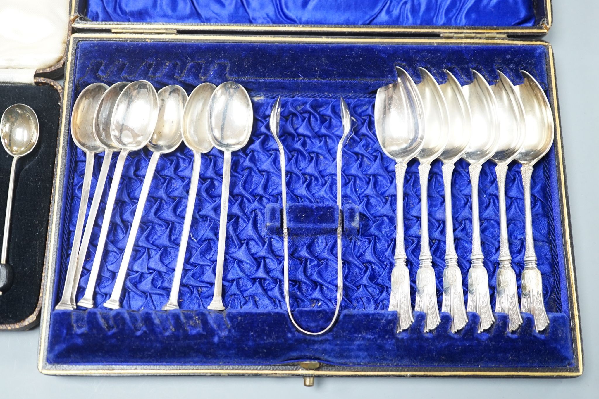 A cased set of six silver bean end coffee spoons, two other sets of six teaspoons and a pair of silver sugar tongs.